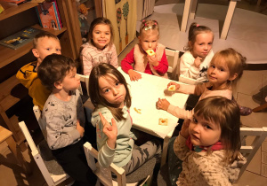 Dzieci jedzą ciasteczka i uśmiechają się do zdjęcia.